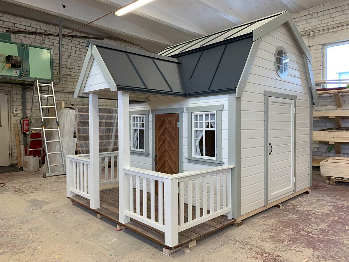 KidsPlayhouses_EU Painted playhouse Grand Farmhouse with awning and pillared terrace in workshop view from right front corner.