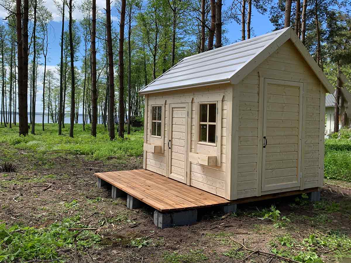 In the woods, KidsPlayhouses_EU is a natural solid wood kids playhouse with Natural wooden terrace, steel roof and flower boxes.