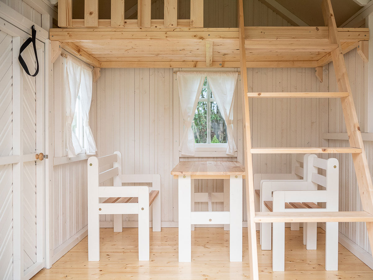 Nordic Nario playhouse interior view, white walls, natural coloured loft and ladder to the loft, white painted kids furniture set: two chairs and table, curtained window in the back by KidsPlayHouses_EU