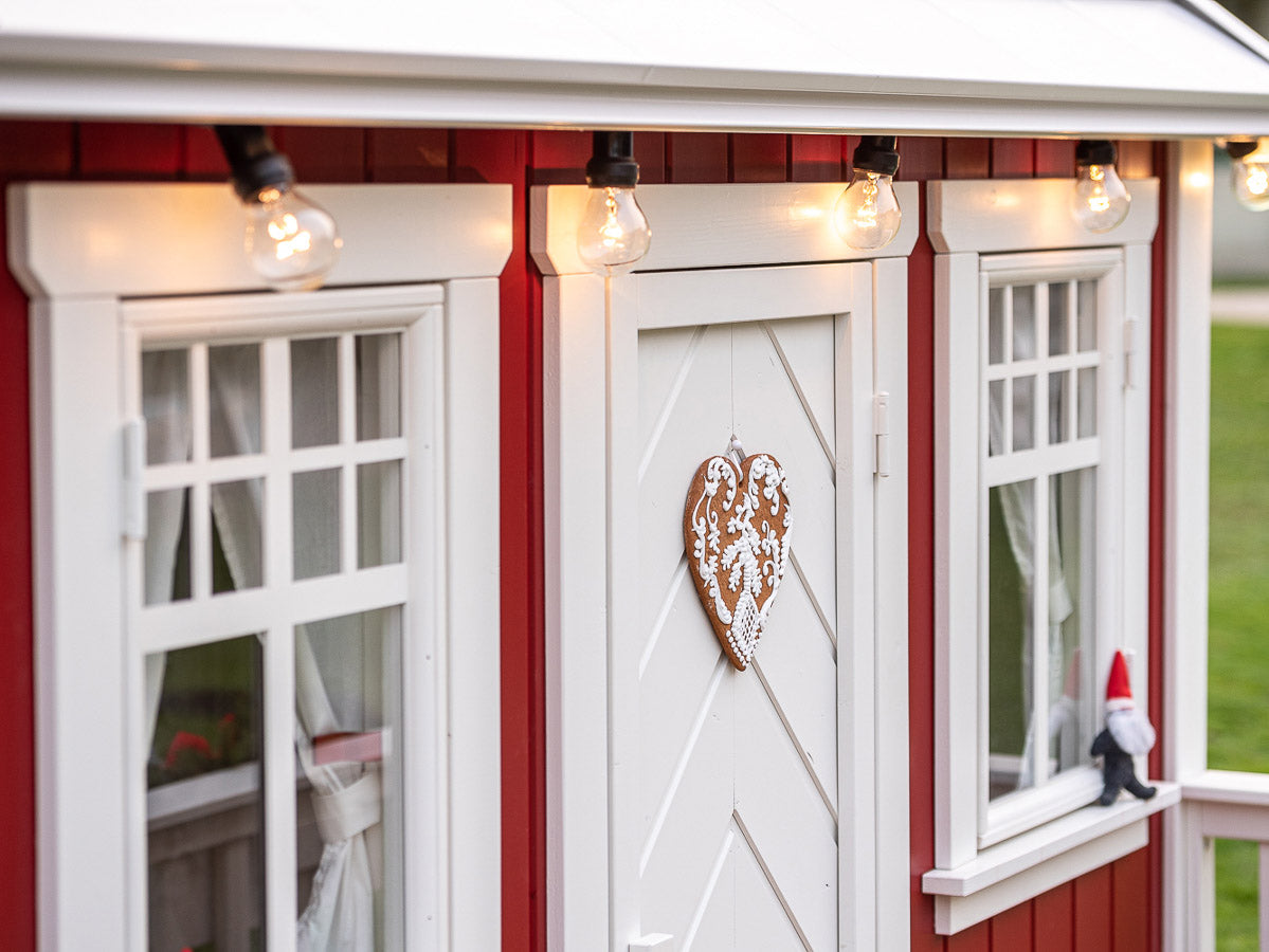 KidsPlayHouses_EU solid wood Nordic Nario playhouse with red painted walls and white window frames, close-up view from the front.