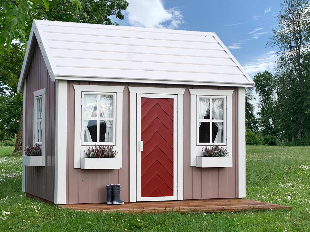 Plum playhouse with beige walls, white window and door sills and white steel roof, kids rubber boots on front terrace by KidsPlayHouses_EU