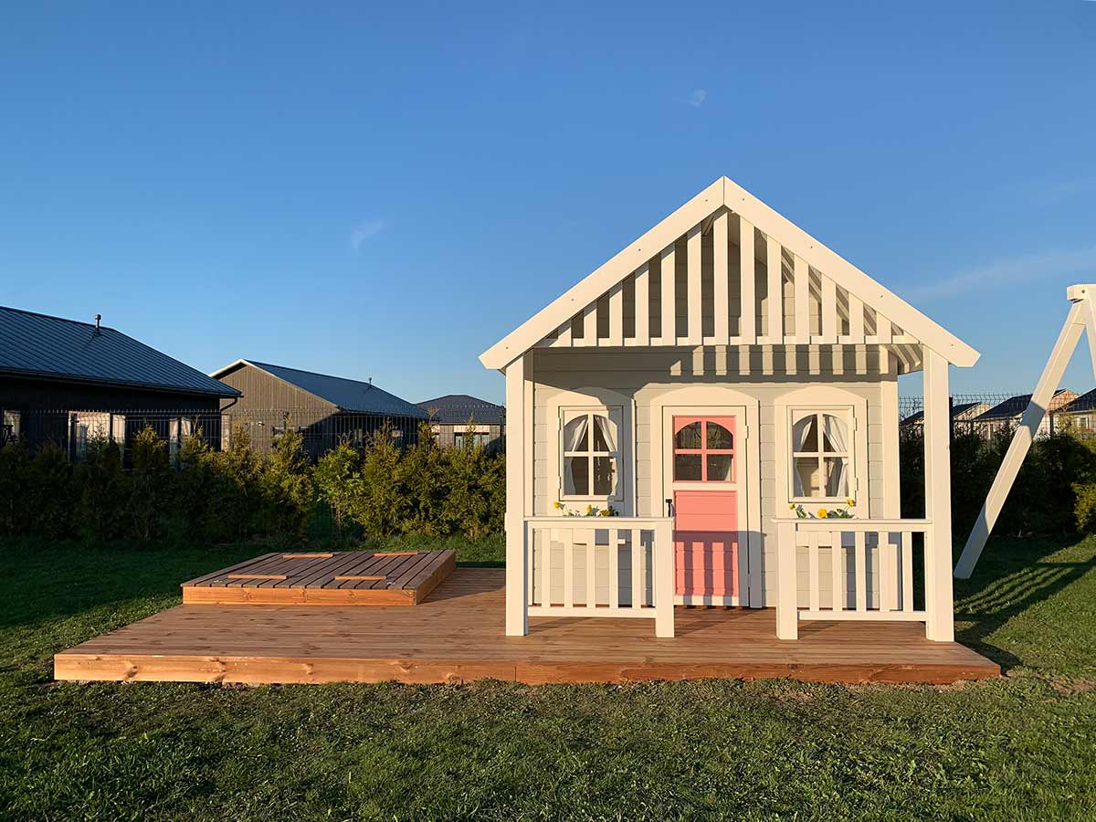 KidsPlayHouses_EU all-wood kids playhouse Beach House front with pink door, white flower boxes and wooden terrace