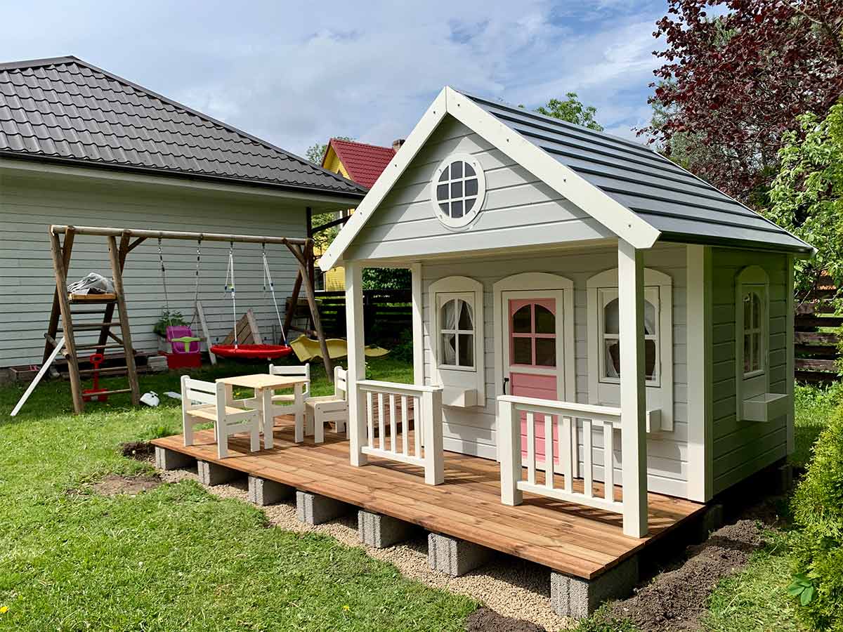 KidsPlayHouses_EU wooden kids playhouse Beach House with white flower boxes, wooden patio and pink door in the back yard