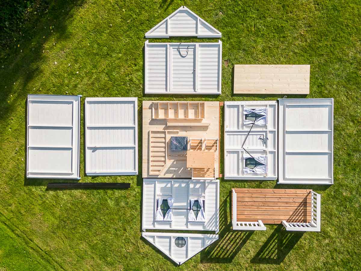 KidsPlayHouses_EU black and white wooden playhouse with finished panels, steel roof, wooden terrace and kids furniture on lawn