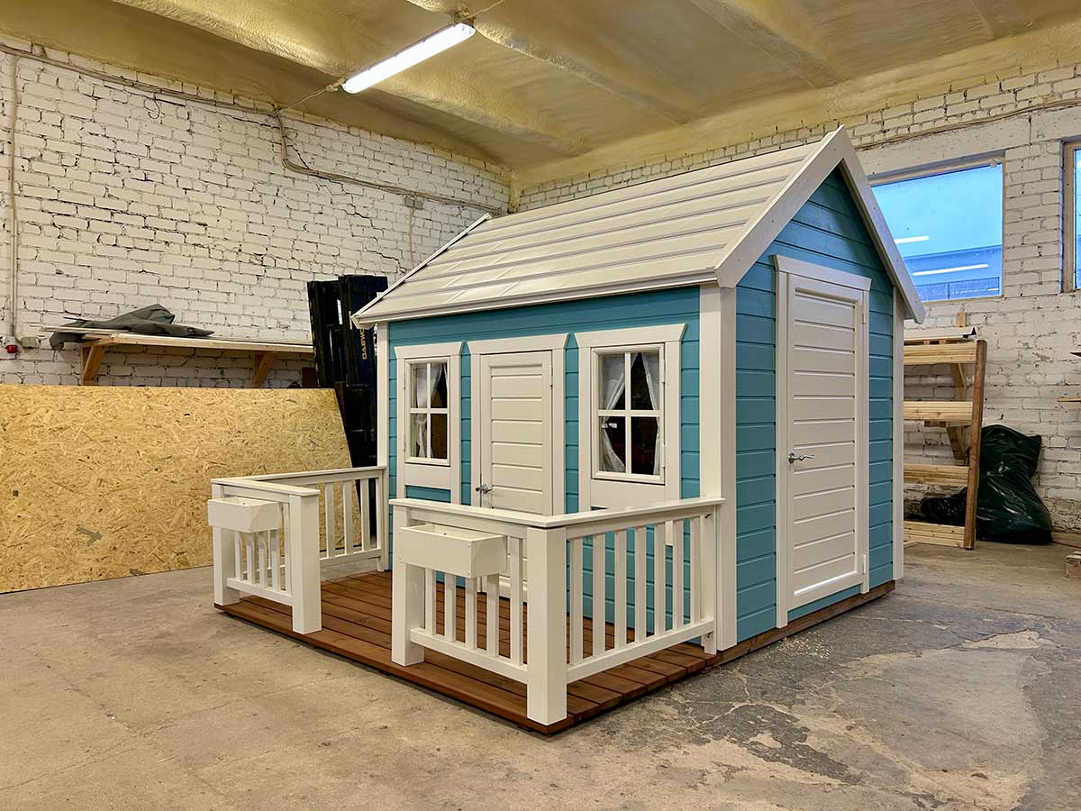 Children’s wooden playhouse with blue siding, white trim, porch and two flower boxes, ready for indoor or outdoor setup.