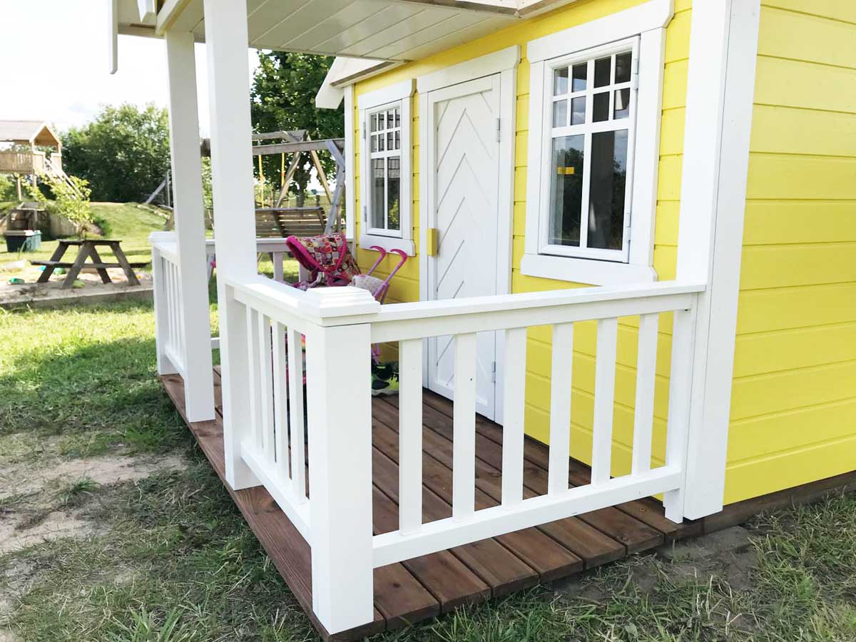 KidsPlayHouses_EU solid wood yellow playhouse Sunny Sadie with wooden terrace and white railing