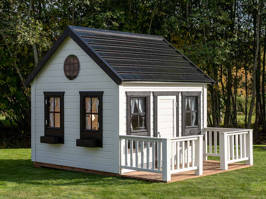 2-Hour Assembled KidsPlayHouses_EU Wooden playhouse with safety glass opening windows, white walls, black coloured steel roof and wooden terrace.