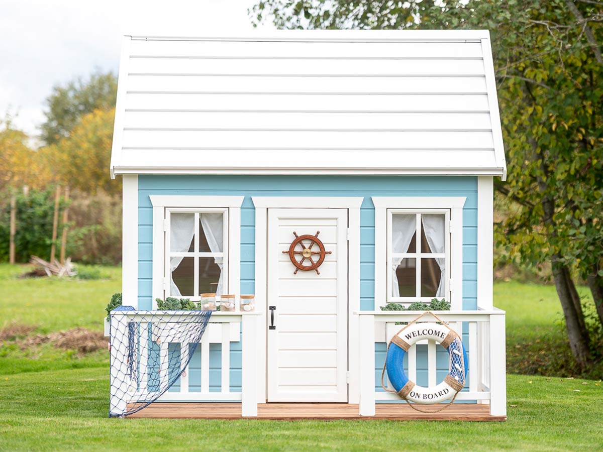 KidsPlayHouses_EU for a wooden playhouse with light blue walls, bright window frames and nautical themed decorations - fishing net, steering wheel.
